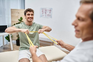 İyi görünümlü olgun bir doktor hastasının dizlerini kontrol ediyor, rehabilitasyon konsepti.