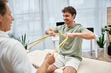 İyi görünümlü olgun bir doktor hastasının dizlerini kontrol ediyor, rehabilitasyon konsepti.