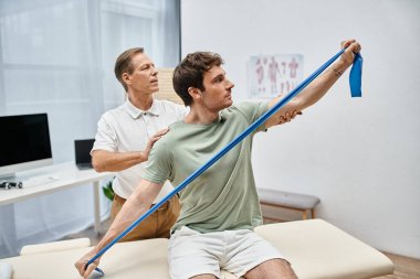 İyi görünümlü olgun bir doktor hastasının dizlerini kontrol ediyor, rehabilitasyon konsepti.