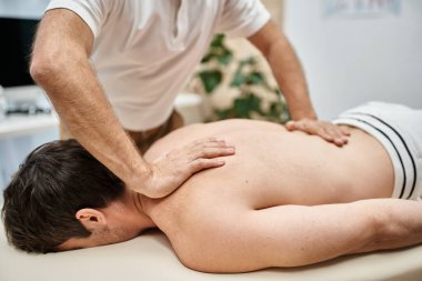 İyi görünümlü olgun bir doktor hastasının dizlerini kontrol ediyor, rehabilitasyon konsepti.
