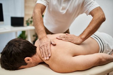 İyi görünümlü olgun bir doktor hastasının dizlerini kontrol ediyor, rehabilitasyon konsepti.