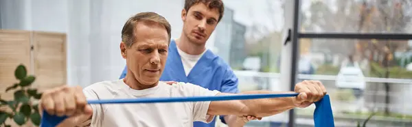 Dedicated Handsome Doctor Helping His Mature Patient Resistance Band Rehabilitation — Stock Photo, Image