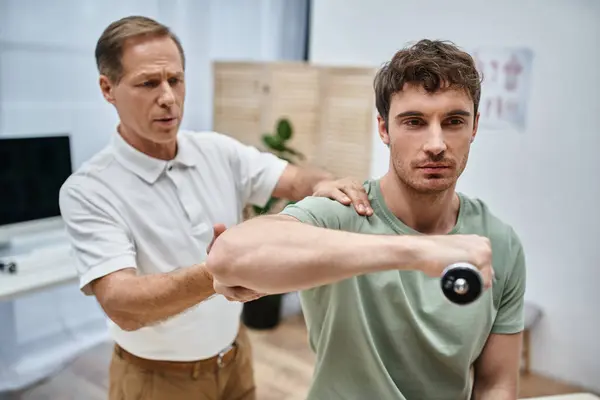 Stock image good looking mature doctor checking up knees of his patient in hospital, rehabilitation concept