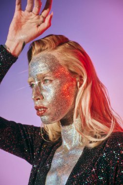 Parlak makyajlı ve parlak elbisesi olan güzel bir genç kadının portresi pembe arka plandan uzağa bakıyor.