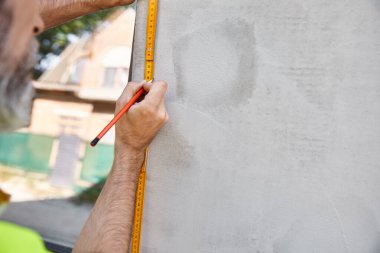 Bulanık inşaat işçisinin elindeki yeni banta odaklan. Pencereyi ölçüyor, kulübe inşaatçısı.