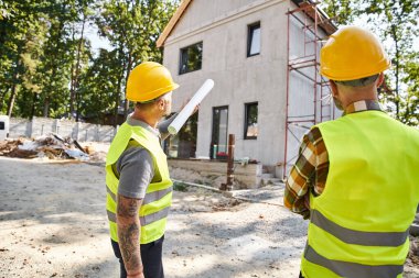 Güvenlik miğferleri takmış özverili kır evi inşaatçılarının arka plan manzarası.