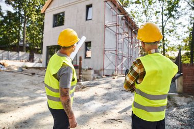 Güvenlik miğferleri takmış özverili kır evi inşaatçılarının arka plan manzarası.