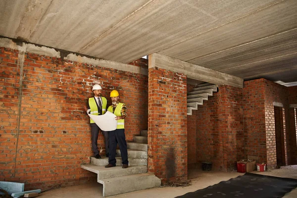 stock image appealing bearded cottage builder and architect working on construction site with blueprint