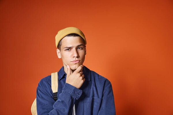 handsome young man in yellow hat thinking about idea against terracotta background