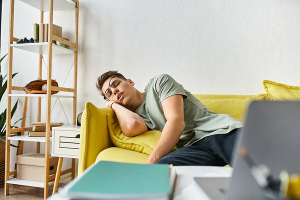 очаровательный студент с каштановыми волосами и очками зрения спит на желтом диване в гостиной