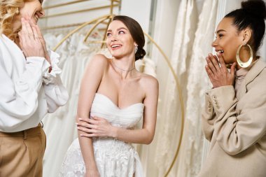 A young brunette bride in a white dress stands alongside two other women, exuding elegance and grace. clipart