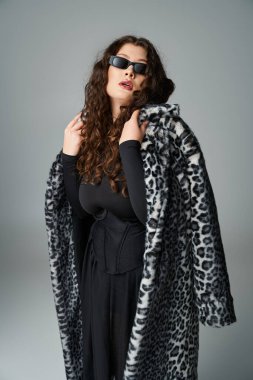 Ayrıca güneş gözlüklü, leopar desenli kürklü ve başını arkaya yaslamış bir kadın.