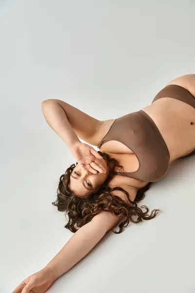 Atraente Curvy Jovem Mulher Lingerie Marrom Com Cabelos Cacheados Deitado — Fotografia de Stock