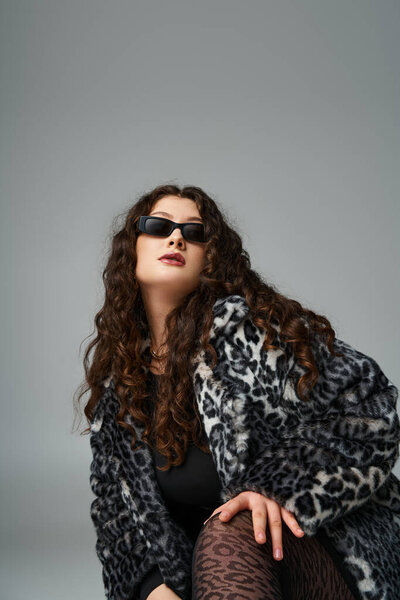 portrait of lovely curvy young woman in leopard fur coat and sunglasses crouching