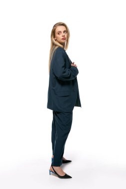 attractive woman with blonde hair in blue elegant blazer posing on white background and looking away clipart