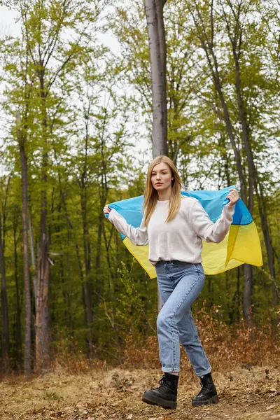 毛皮としてウクライナの国旗で体を覆う森に立っているかわいい金髪の女性 — ストック写真