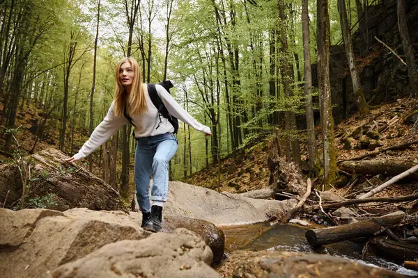 背着背包在森林里的山河岩石上远足和保持平衡的女人 单身女性游客 — 图库照片