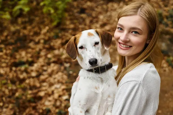 stock image Cute dog sitting with beautiful female blonde woman in forest looking at camera while hiking