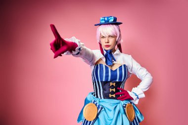 Parlak anime elbiseli güzel bayan Cosplayer pembe arka planda kameraya bakıyor.