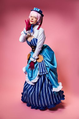 Mavi şapkalı ve canlı giyinmiş, pembe arka plandaki kameraya bakan çekici seksi bayan Cosplayer.