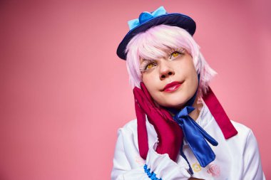 Çekici, modaya uygun bir kadın sevimli bir anime karakteri canlandırıyor ve pembe arka plana bakıyor.