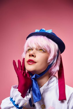 Çekici, modaya uygun bir kadın sevimli bir anime karakteri canlandırıyor ve pembe arka plana bakıyor.
