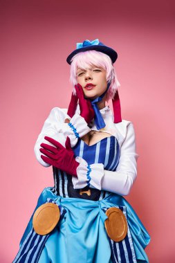 Mavi şapkalı ve canlı elbiseli çekici bayan Cosplayer kameraya bakıyor.