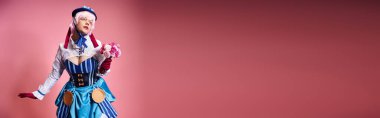 Canlı giyinmiş, elinde pembe çiçekler olan sevimli bayan Cosplayer 'lar pembe arka planda, pankartta gözlerini kaçırıyorlar.