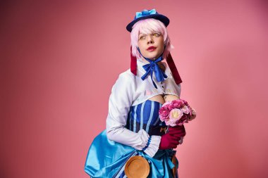 Çekici, canlı giyinmiş, elinde pembe çiçekler olan ve pembe arka plana bakan kadın Cosplayer.