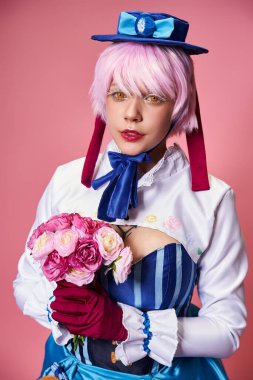 Canlı kostümlü, elinde pembe çiçekler olan ve kameraya bakan sevimli bayan Cosplayer.