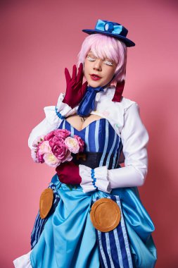Güzel bir kadın elinde pembe çiçeklerle sevimli bir anime karakteri canlandırıyor. Gözleri kapalı poz veriyor.