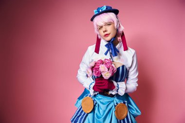 Canlı kostümlü, elinde pembe çiçekler olan ve kameraya bakan güzel bir bayan Cosplayer.