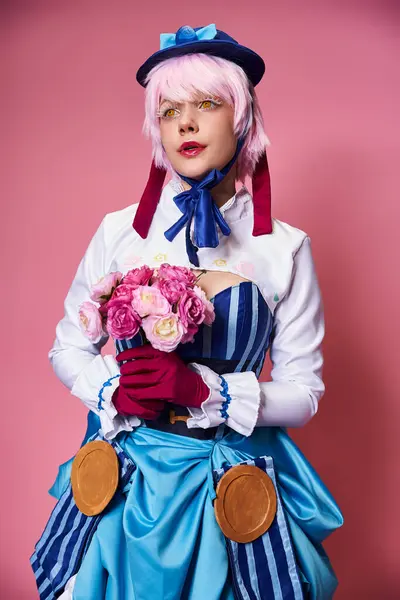 stock image cute stylish female cosplayer in vivid attire holding pink flowers and looking away on pink backdrop