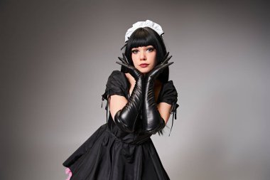 charming sexy female cosplayer in tempting maid costume looking at camera on gray background clipart