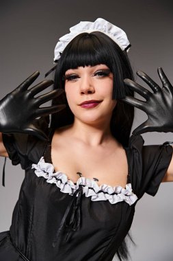 Gri arka planda kameraya bakan baştan çıkarıcı hizmetçi kostümlü güzel seksi kadın Cosplayer.