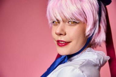 Canlı giyinmiş, pembe arka planda kameraya gülümseyen neşeli ve çekici bir bayan Cosplayer.