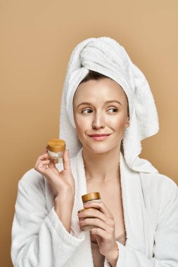 Beyaz cüppeli büyüleyici bir kadın zarif bir şekilde yüzünde ışıl ışıl bir gülümseme olan bir krema kavanozunu tutuyor..