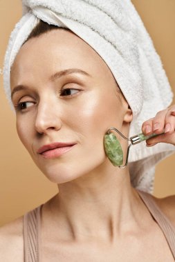 Kafasında havluyla çekici bir kadın, yüzünü ustalıkla yuvarlıyor..