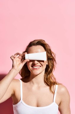 Beyaz atletli büyüleyici bir kadın zarif bir şekilde gözlerine beyaz bir krem sürüyor..