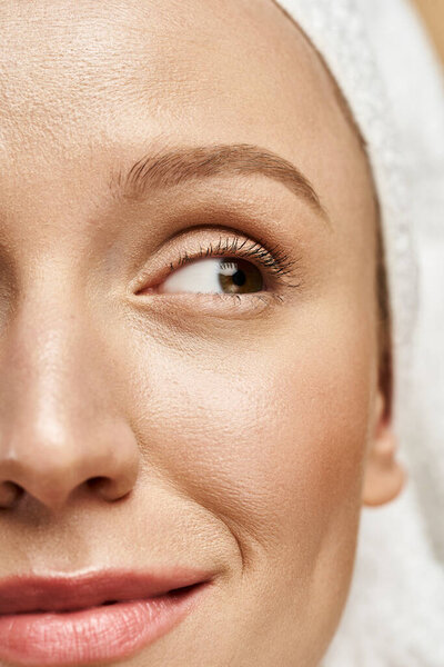 A natural beauty exudes elegance with a towel draping her head in a close-up portrait.