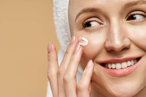 A natural beauty woman smiles joyfully with a towel wrapped around her head.
