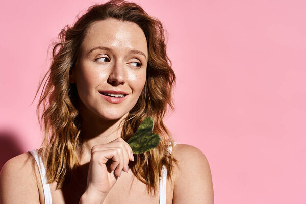 An attractive woman delicately holds gua sha, showcasing her natural beauty and grace.