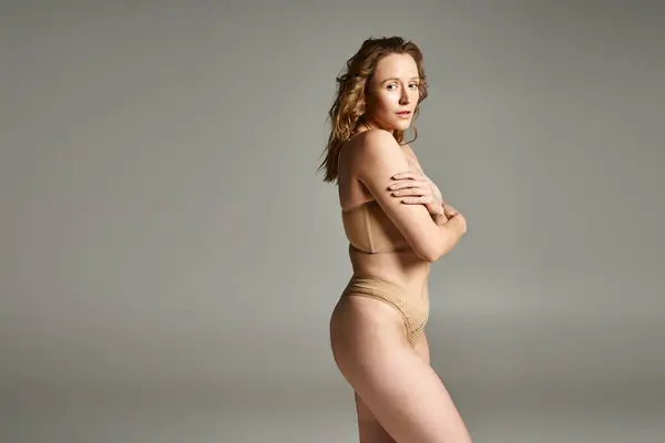 stock image A natural beauty strikes a pose in tan underwear, exuding confidence and elegance.