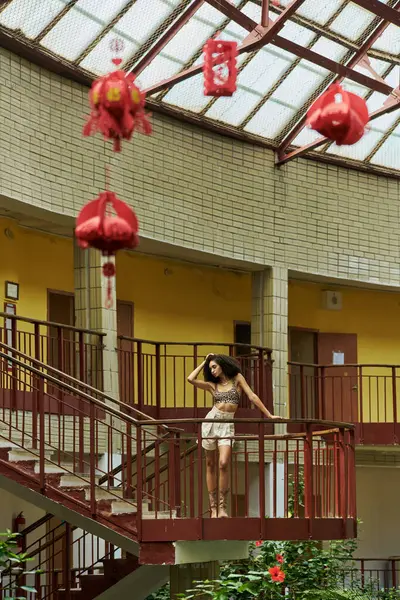 Uzaktan bak, yeşil ve kırmızı fenerlerle çevrili, hayvan desenli şık siyah kadın.