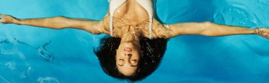 Mavi havuz suyunda sırtüstü yüzen Afro-Amerikalı genç bir kadın, sakin bir afiş.