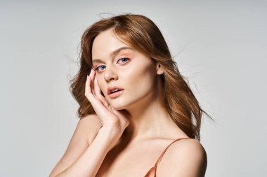 Doğal makyajlı güzel bir kadının güzel portresi. Yüzüne yakın elleriyle kameraya bakıyor.