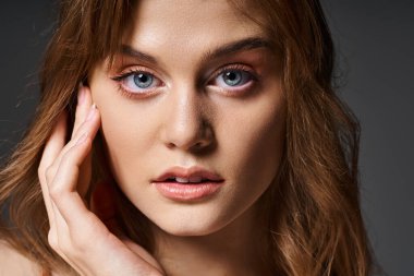 Gri arkaplana dokunmuş şeftali rengi doğal makyajlı güzel bir kadın portresi.