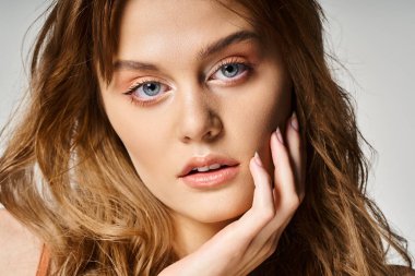 Gri arkaplana dokunmuş şeftali rengi doğal makyajlı güzel bir kadın portresi.