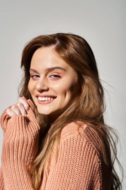 Gri arka planda çilleri ve şeftali makyajıyla gülen neşeli kadının yan görünümü.