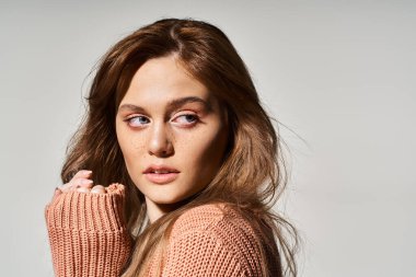 Şeftali makyajlı ve gri arka planda çilleri olan çekici bir kadın portresi.